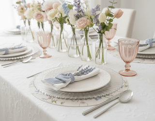 Elegant table setting with floral arrangements, light blue accents, and pink glassware.