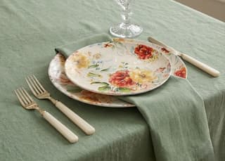 beautiful floral pattern in rich, warm hues of yellow, orange, and red, perfectly complemented by a subtle sage-green linen tablecloth shavous