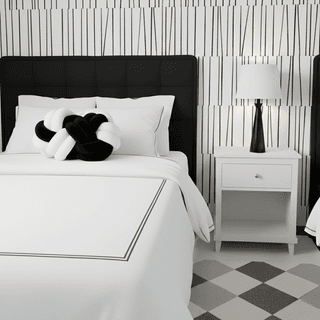 Monochromatic bedroom with knot pillow, white bedding, black headboard and patterned wallpaper.