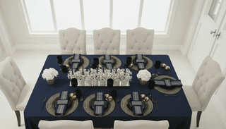 Overhead view of dining table set with navy tablecloth, beige chairs, and floral centerpiece.