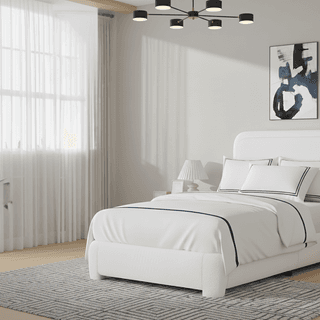 Bedroom with white bed, blue-striped linens, abstract art, and modern chandelier.